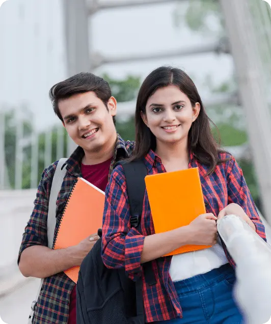 Two diverse students smiling and holding notebooks while on a UK university campus bridge