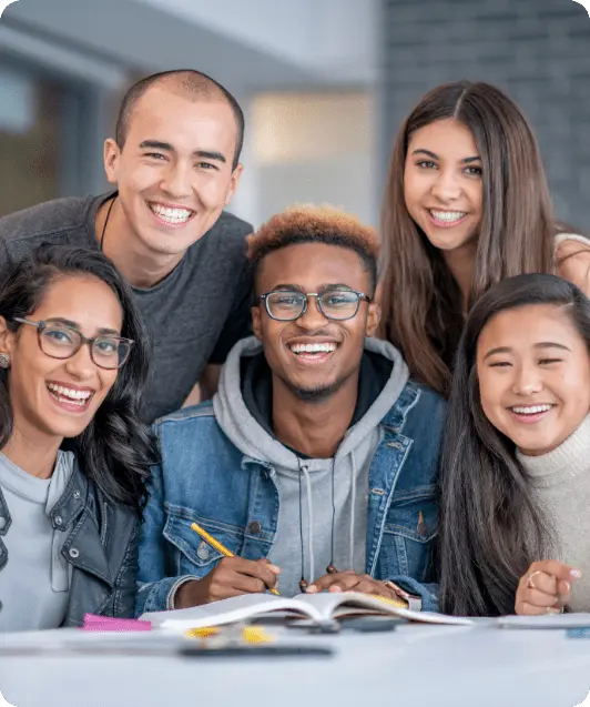 A diverse group of five happy students studying together on a modern USA university campus